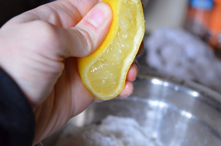 Lemon being squeezed into powdered sugar.