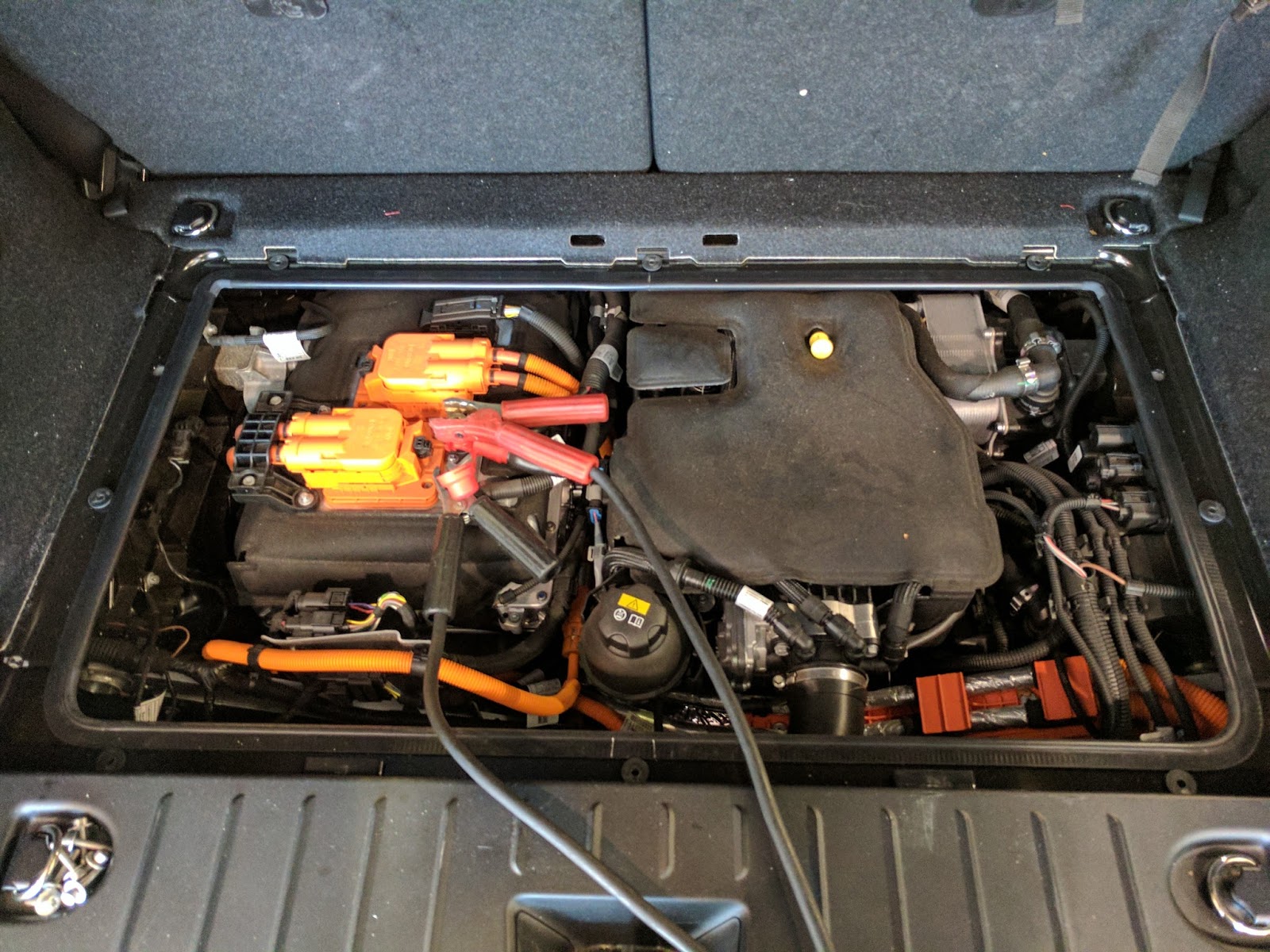 An i3 with the range extender option exposed. The electric motor and power electronics are on the left, with the jumper cables attached.