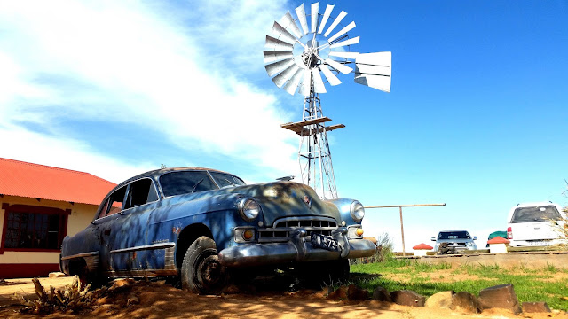 Old fashioned car next to a windmill at Canyon Road House Namibia