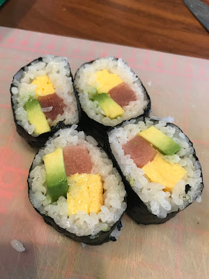 Four sliced nori rolls containing egg, avocado, cucumber and tuna