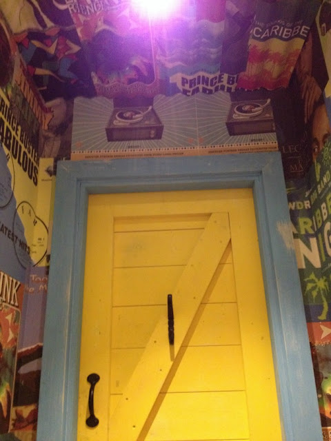 bright yellow door and fantastic wallpaper of posters of Bob Marley 