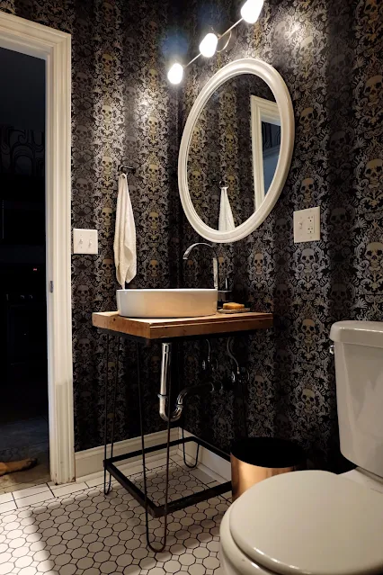 view of diy bowling alley pedestal sink and skull wallpaper