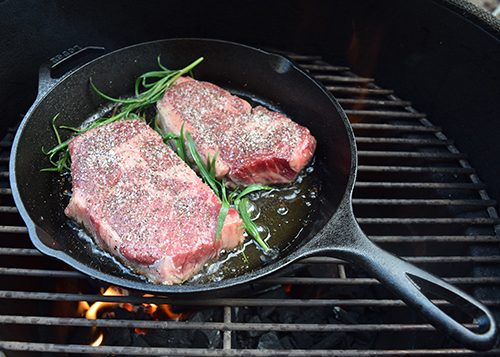 Certified Angus Beef prime ribeye steaks in Lodge Cast Iron pan on a Big Green Egg