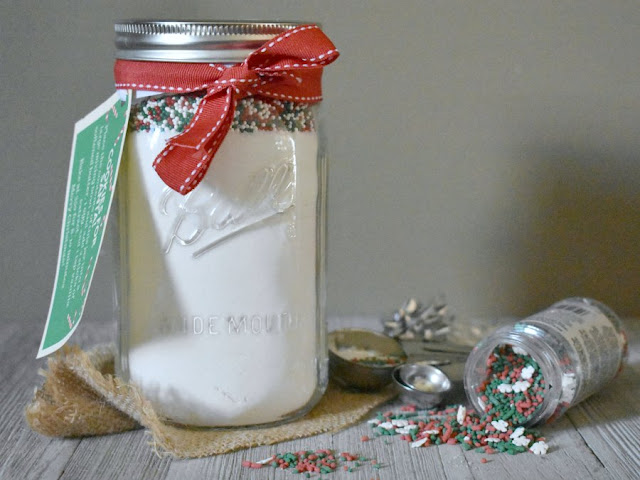 These sweet sugar jars are loaded with festive sprinkles that are ready to be baked into sugar cookies. They make great gifts for teachers, friends or the big man himself! jar of dry ingredients for cookies and sprinkles with tipped sprinkle bottle nearby