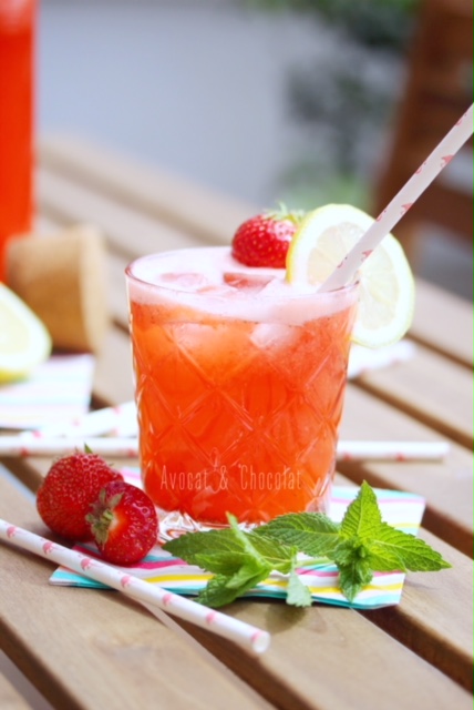 alt="limonade fraise dans 2 bouteilles en verre et un verre décoré d'une paille, d'une fraise et d'une rondelle de citron"