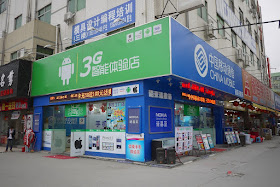 Store in Nanping, Zhuhai, China displaying signs with logos for Android, Apple, Nokia, and more.