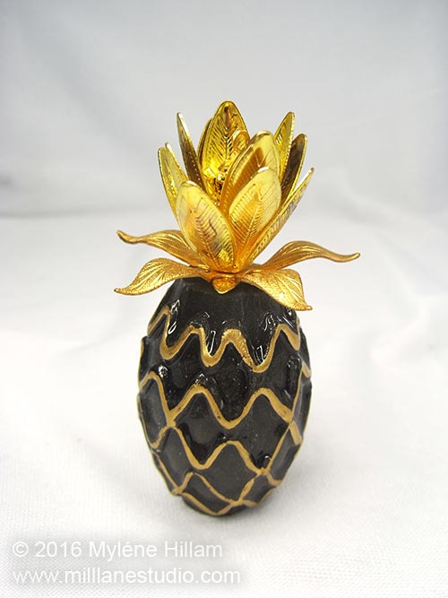 Handmade pineapple-shaped resin Faux Egyptian Perfume bottle created by Myléne Hillam of Mill Lane Studio. These are assembled with lots of bead caps, a smattering of beads and crystals and a few filigree stampings. Full tutorial for how to make these.