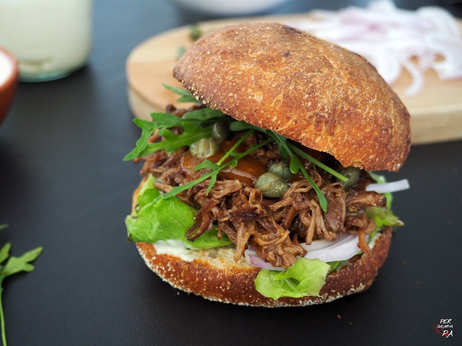 Falda de ternera cocinada a baja temperatura y aderezada con una salsa con los jugos del asado, miel y mostaza. Servida en bun de pan deli.