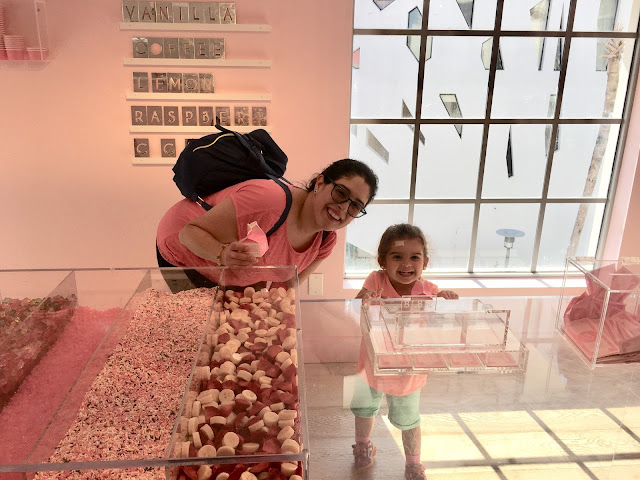 Mother and daughter posing for a photo by a fake toppings bar art installation