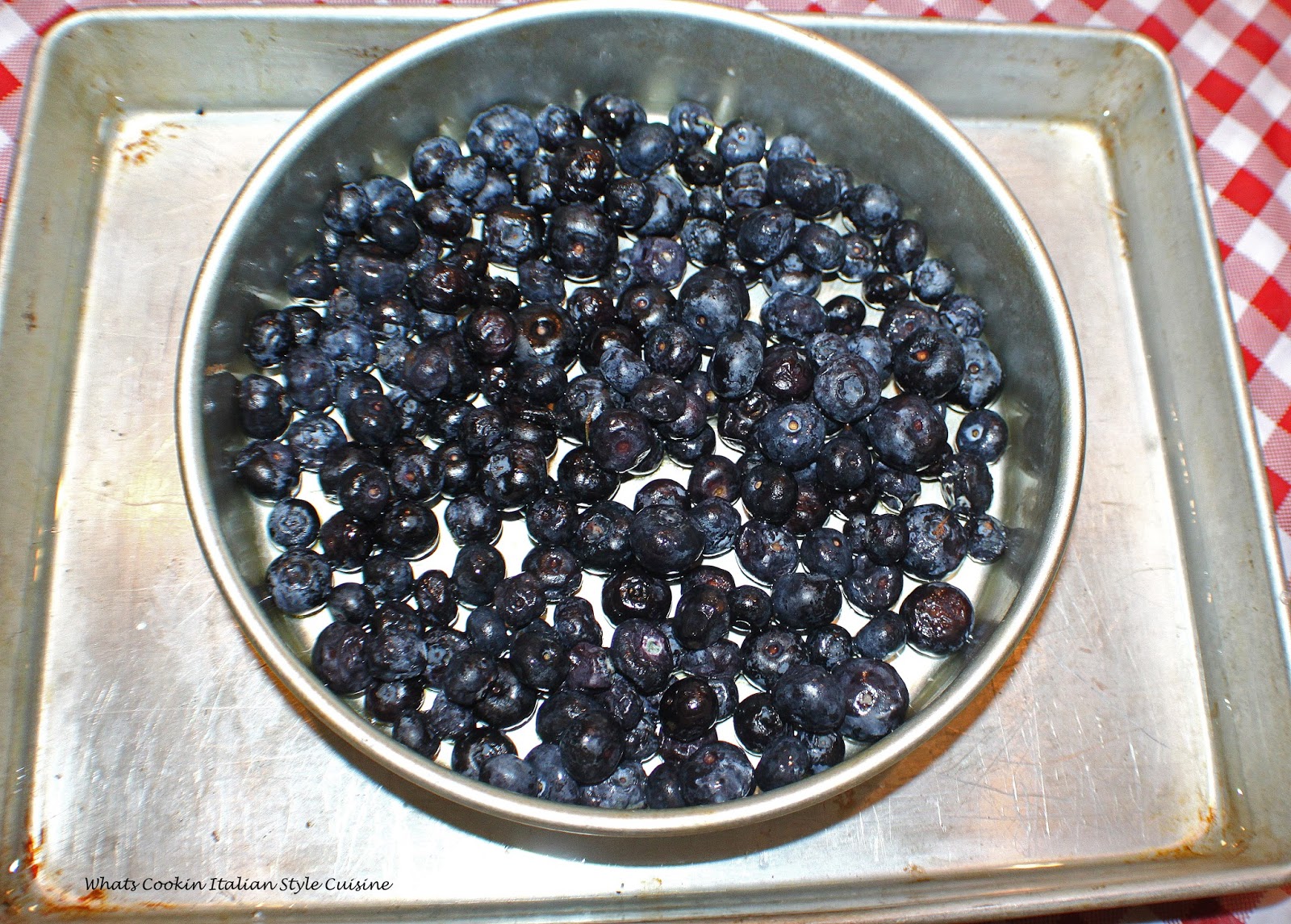 Blueberries in a round pan ready for the batter for flan. The egg mixture will pour on top of the blueberries preparing to make the flan