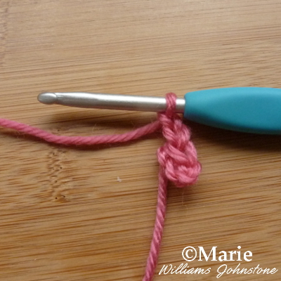 Pink yarn on turquoise crochet hook