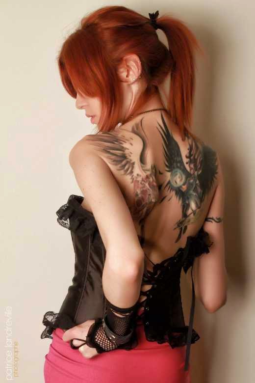 Foto de una preciosa mujer peliroja con tatuaje de angeles en la espalda