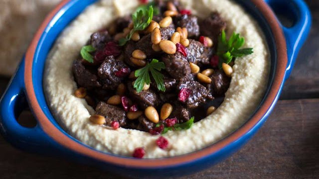 Spiced beef with hummus and pine nuts in a serving dish