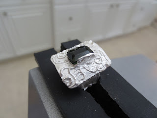 fired metal clay ring in a vise, ready to set the tourmaline