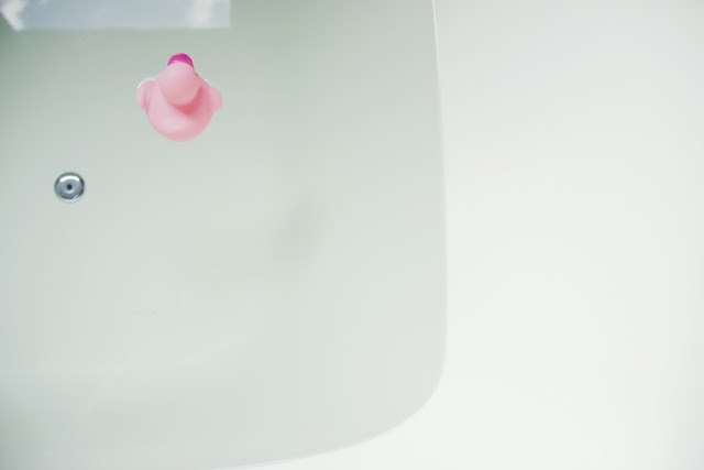 A bath filled with clear water and a pink rubber duck floating in it