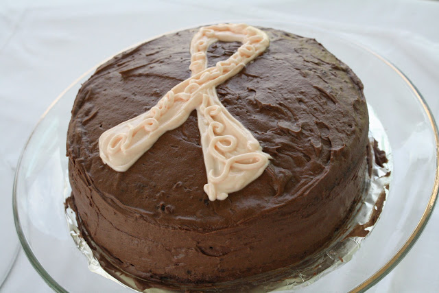 A top down shot of a cake with chocolate frosting and pink ribbon.