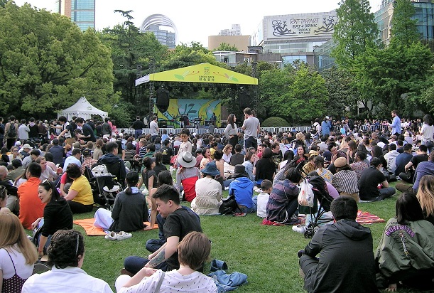 芝生に座って演奏をひたすら待つ観客と特設ステージ