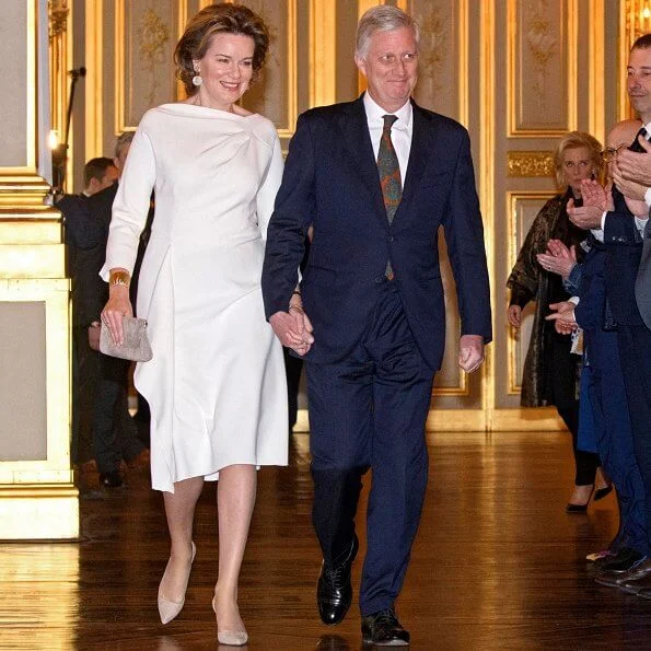Queen Mathilde wore a coat from Autumn Winter 2016-2017 collection of Dries Van Noten. Queen wore a white satin midi dress by Natan