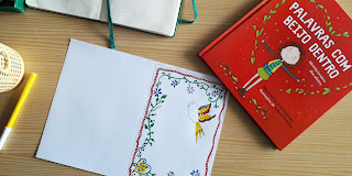Um postal com desenhos inspirados nos lenços dos namorados portugueses e o livro "Palavras com beijo dentro"