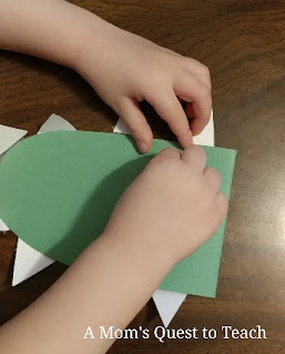 Taping or gluing white construction paper triangles to green construction paper alligator craft head