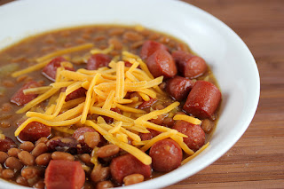 Baked beans and hot dogs in a white bowl