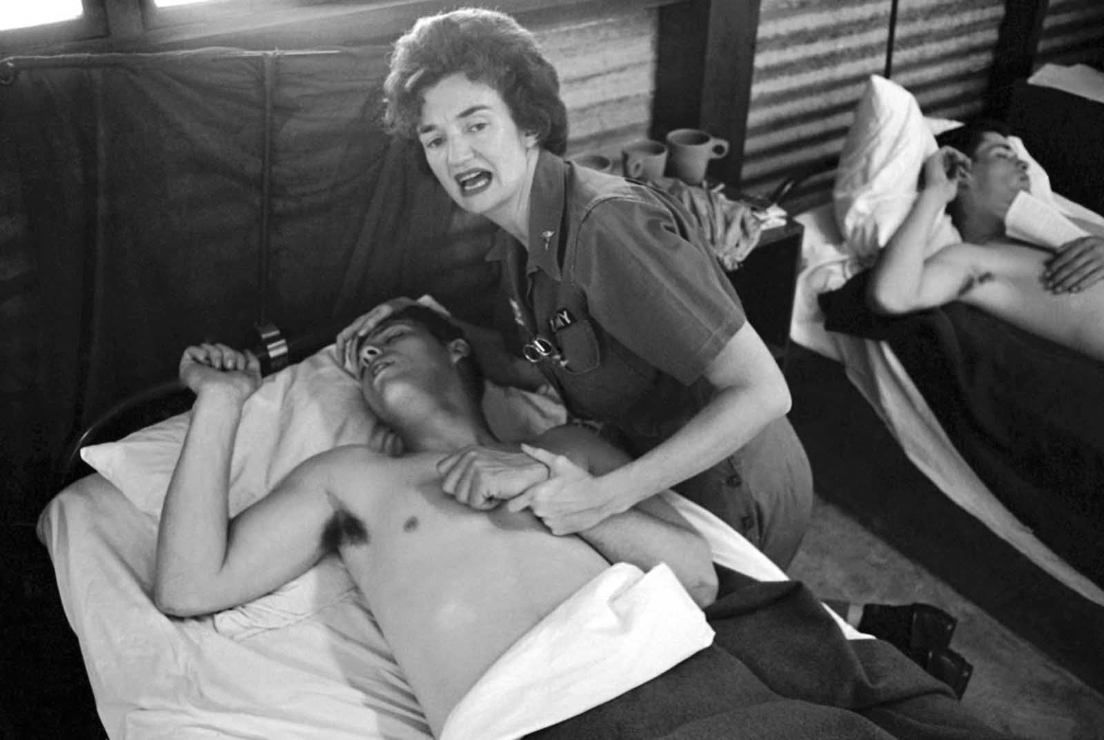 A nurse attempts to comfort a wounded U.S. Army soldier in a ward of the 8th army hospital at Nha Trang in South Vietnam on February 7, 1965. The soldier was one of more than 100 who were wounded during Viet Cong attacks on two U.S. military compounds at Pleiku, 240 miles north of Saigon. Seven Americans were killed in the attacks.
