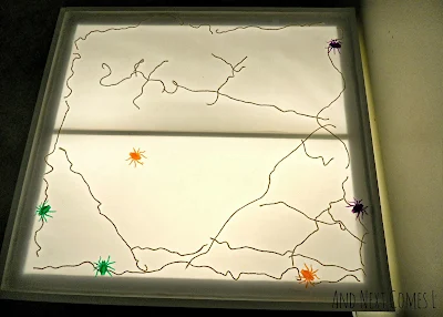 A giant spiderweb with colorful spiders on the light table from And Next Comes L