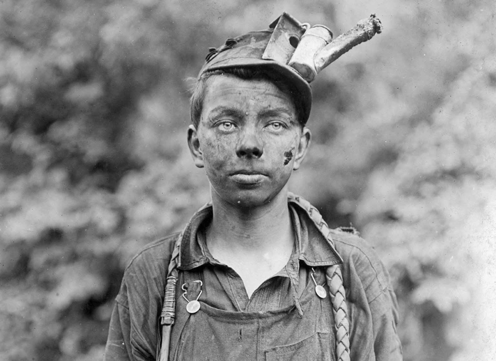 A young driver in the Brown Mine in Brown, West Virginia, in September of 1908. He had been driving pack animals for one year, working from 7 a.m. to 5:30 p.m. daily. The device attached to his cap is an oil-wick cap lamp, which would be lit when the boy was working in the mine tunnels.