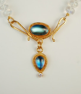 gold colored clasp with an oval and pear shaped white stone with strong blue highlights