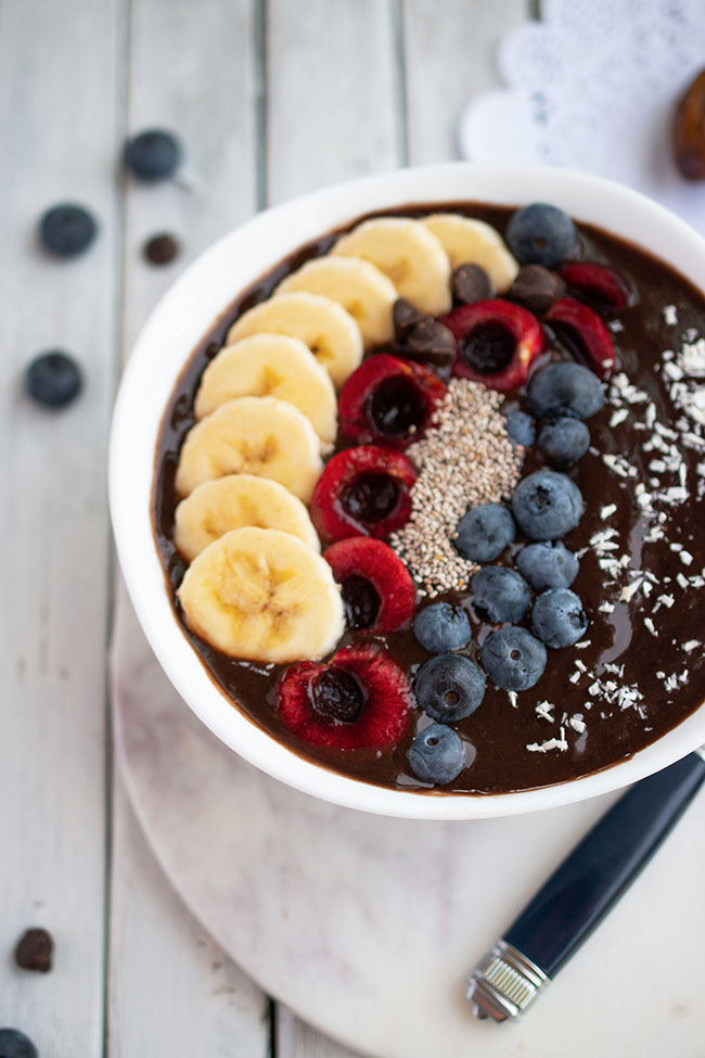 Vegan and gluten-free chocolate date smoothie bowl with fruit toppings closeup