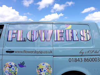 Flowers printed vinyl letters with pastel colour stripes on a duck egg blue van. There is also black vinyl letters with contact details.