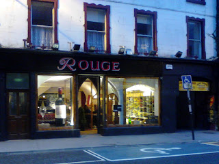 Twilight photo of Rouge Cafe, Galway - with a giant wine bottle in the front window