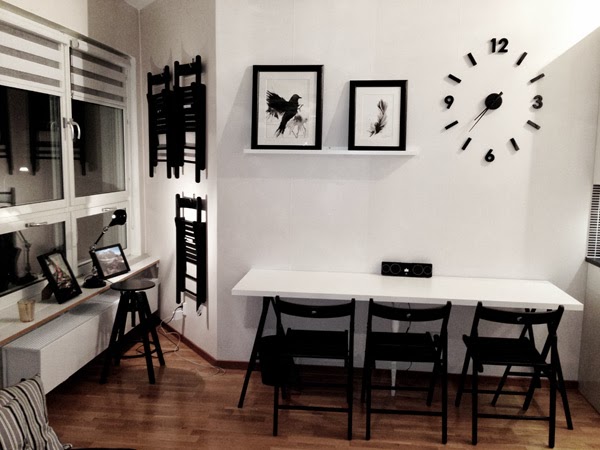 lägenhet i stockholm, svarta och vita prints, artprints fågel, svart fågel, svart och vitt kök, svart klocka, vita väggar, stolar på väggen, tavlor prints, tavlor i köket, tavellist, vit hylla i köket