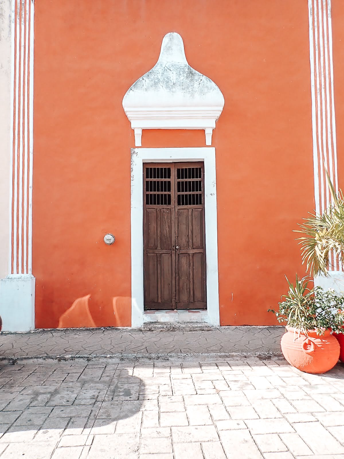façade d'une maison colorée en orange dans la ville de valladolid au mexique avec des liserés blancs et une porte en bois