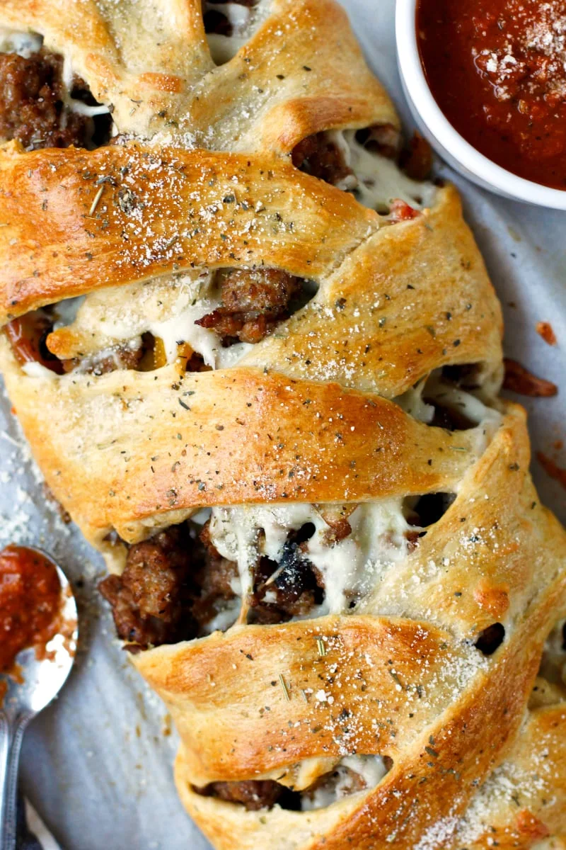 This Italian Sausage Crescent Braid is loaded with sausage, mozzarella cheese, and veggies all wrapped in a golden crescent roll crust.  It bakes in just 15 minutes, making it the perfect choice for a weeknight dinner! #italiansausage #crescentrolls #30minutemeal
