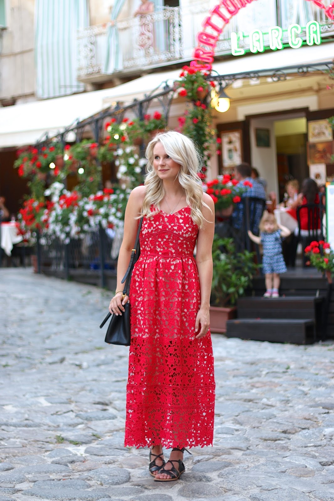 lady wanders around small town italy in bright red lace midi dress and loose curls in her hair