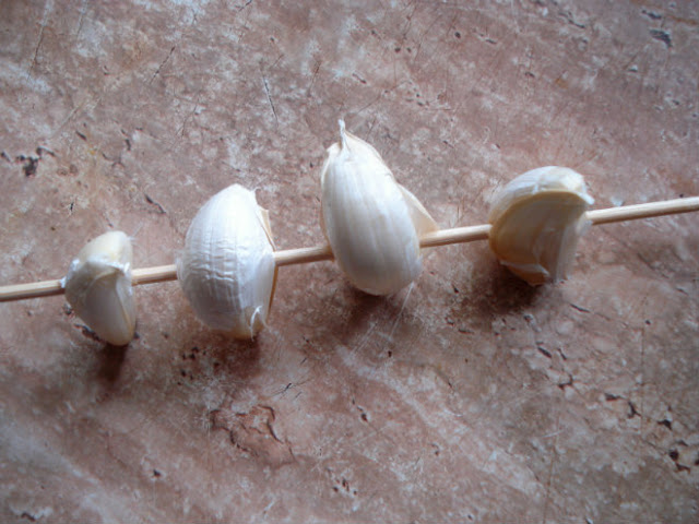 Thread garlic cloves onto a skewer.