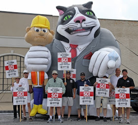 Eight members of Teamster Local 727 hold picket signs, demand fair negotiations.