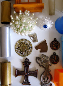 Three metal tubes, a selection of metal charms and two vintage brooches.