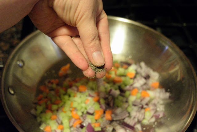 Pepper being added to the vegetables in the pan.