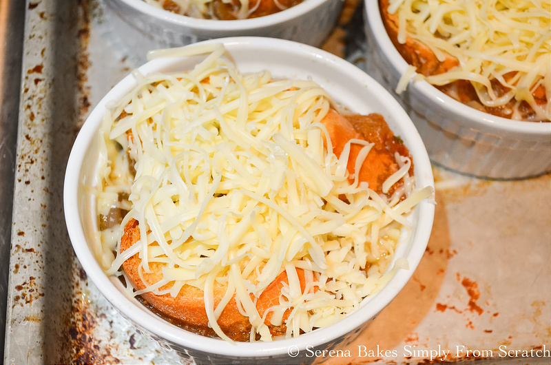 Oven safe bowls filled with French Onion Soup covered with toasted baguette and grated gruyere cheese.