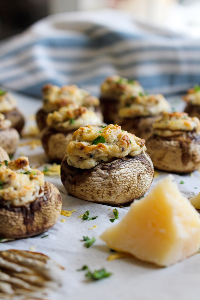 Cream Cheese Stuffed Mushrooms on a parchment-lined baking sheet with a blue and cream kitchen towel behind them.
