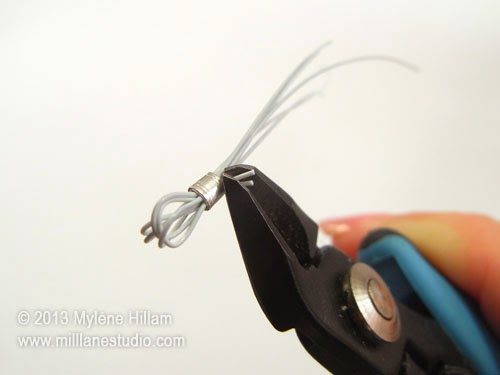 Using flush cutters to trim away excess beading wire right up to the crimp tube