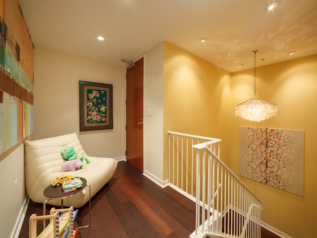 Picture of large white sofa and yellow walls on the upper level of duplex