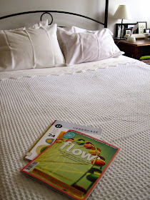 Freshly-made bed with a white waffle-weave blanket and a copy of Flow magazine and Uppercase magazine on it.
