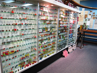 Rows of metal cars displayed on shelves in glass cabinets lining the walls.