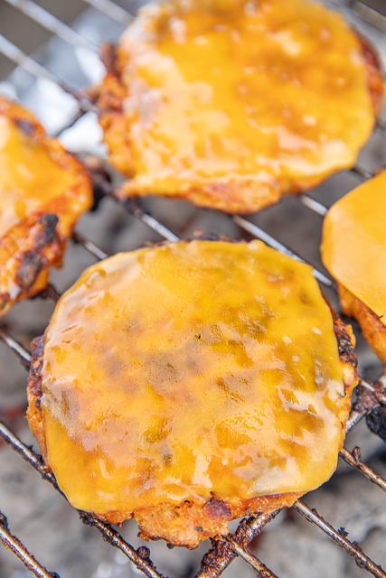Buffalo Chicken Burgers Recipe - SO good! I like these better than regular beef burgers! SO much amazing flavor! Ground chicken, bread crumbs, cheddar cheese, ranch seasoning, and buffalo seasoning. Can form into patties and freeze for later. Can cook on the grill or on the stove. Brush with hot sauce to kick up the heat. Top with ranch or blue cheese dressing. Also great topped with slaw! #bbq #grilling #chicken #groundchicken #burger #chickenburger ground chicken burgers cooking on the grill