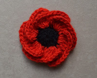 "Hope Bloom" by Jenny King after blocking. The six overlapping red petals are arranged evenly and are open to reveal the black centre.