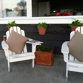 Two adirondack chairs on a holiday house porch.