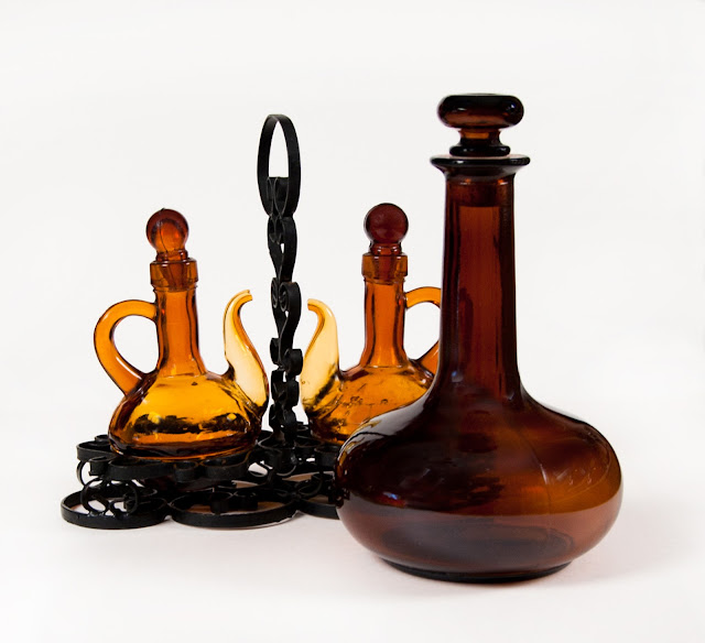 A wine or water jug in amber glass, with a cruet set in metal older, also in amber glass.